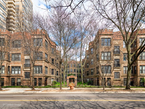 Front view of a multi-story brick residential building with large windows.