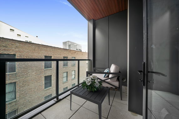 Balcony with seating area overlooking neighboring building.