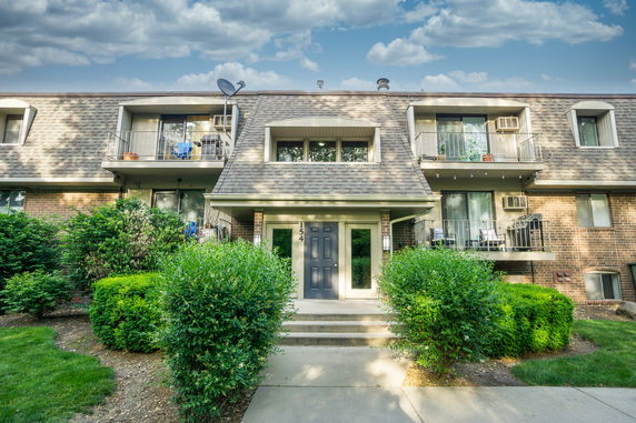 Front view of a multi-story residential building with balconies and a central entrance.
