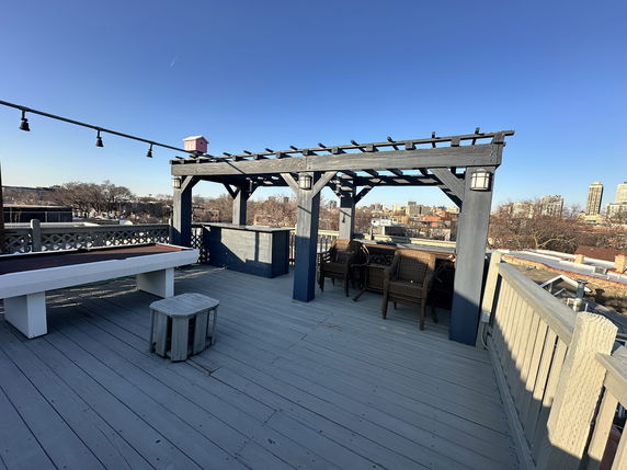 Rooftop with wooden pergola, outdoor seating, and a birdhouse view.