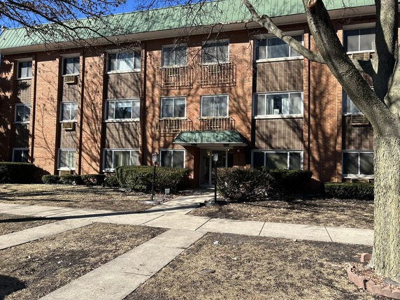Front view of a three-story brick apartment building with multiple windows.