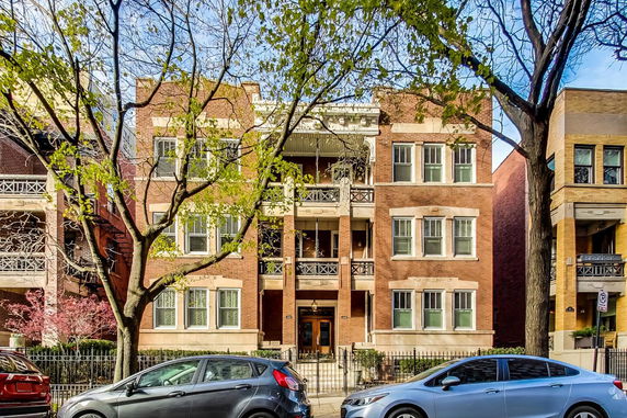 Front view of a three-story brick apartment building with balconies.