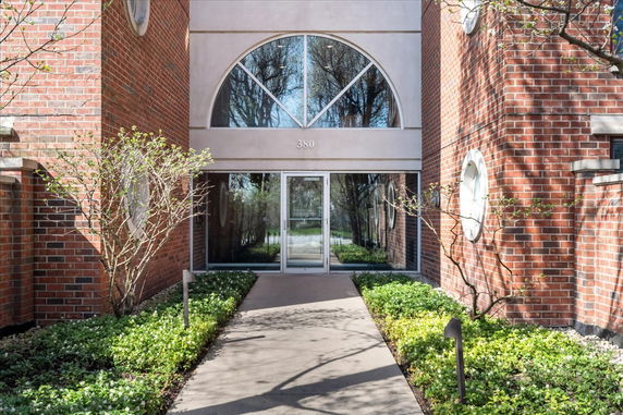 Front view of a brick building entrance with glass doors and large windows above.