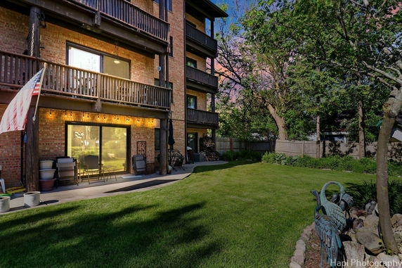 Rear view of a multi-story brick building with balconies and a patio area.