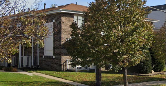 Front view of a two-story brick house with a small porch.