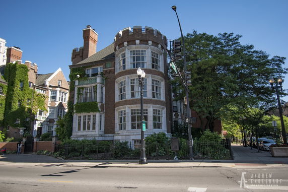 Front view of a multi-story brick building with large windows and a castle-like turret.