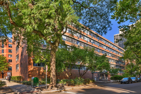 Front view of a multi-story building with red brick exterior and numerous windows.