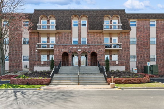 Front view of a brick apartment building with balconies and a central entrance.
