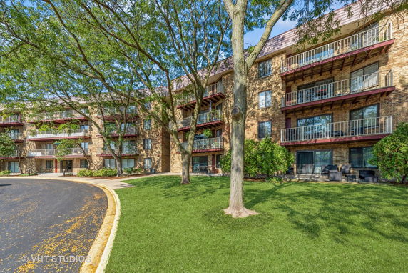 Front view of a multi-story apartment building with balconies and brick facade.