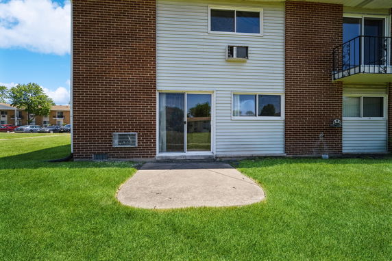 Front view of a residential building with a brick facade and sliding glass door.