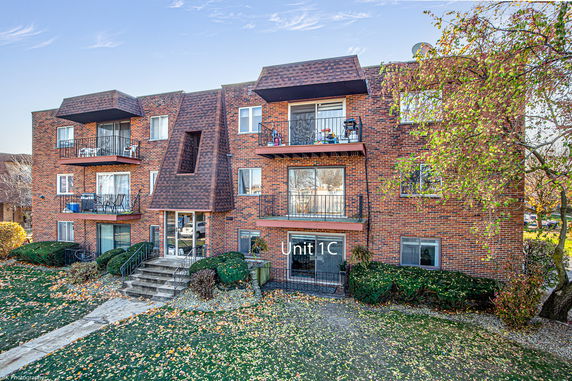 Front view of a multi-story brick apartment building with balconies.