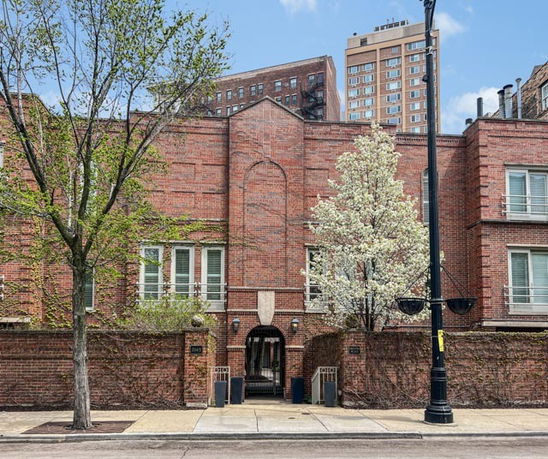 Front view of a brick building with arched entrance and multiple windows.