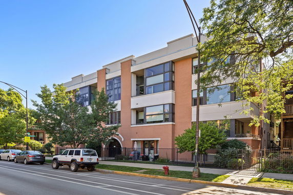 Front view of a multi-story building with large windows and a brick facade.