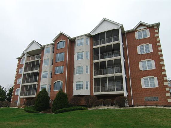 Front view of a multi-story brick apartment building with enclosed balconies.