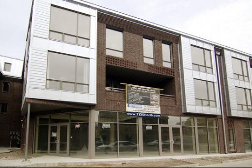 Front view of a modern multi-story commercial building with large glass windows and brick facade.