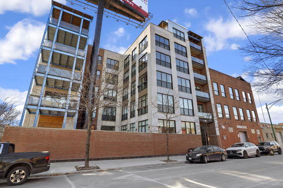 Front view of a multi-story residential building with large windows and brick facade.