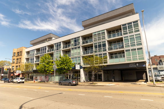 Front view of a modern multi-story building with large glass windows and balconies.