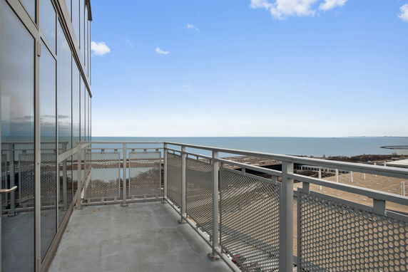 Balcony view overlooking a large body of water with buildings in the distance.
