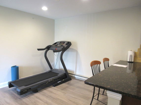 Indoor room with a treadmill and chairs next to a countertop.