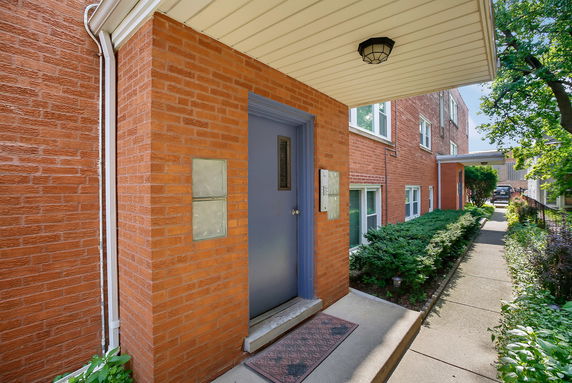 Front view of a brick building entrance with a blue door and adjacent pathway.