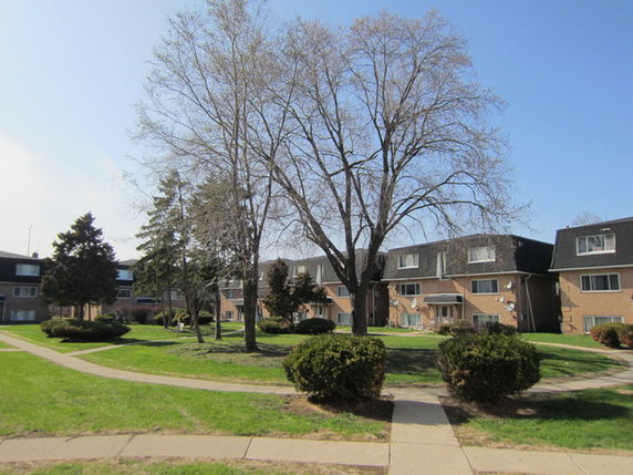 Front view of a large residential building with multiple units and brown brick facade.