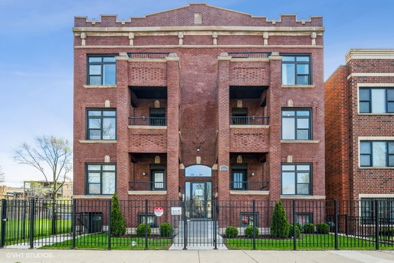 Front view of a multi-story brick apartment building with balconies.