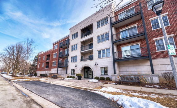 Front view of a multi-story apartment building with balconies and brick facade.