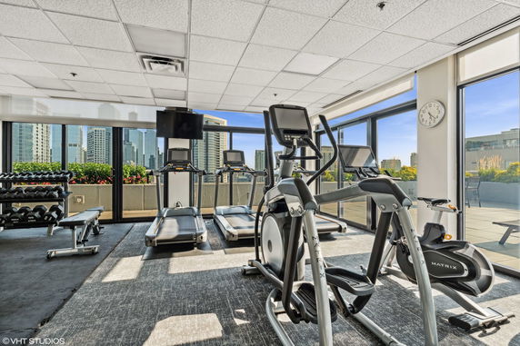 Gym area with exercise equipment and large windows overlooking cityscape.