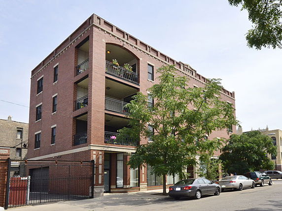 Front view of a multi-story brick apartment building with balconies.