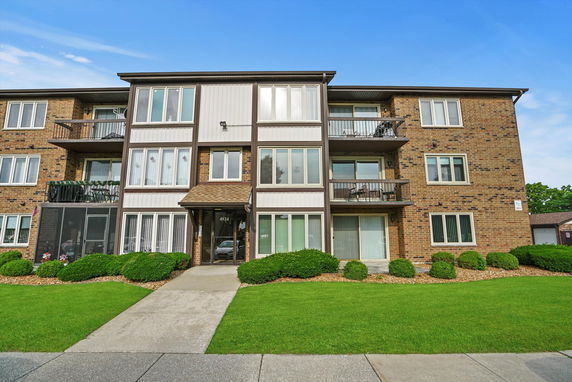 Front view of a three-story brick apartment building with balconies.