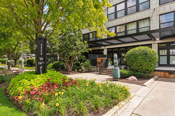 Front view of a multi-story building with large windows and landscaped garden.
