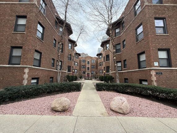 Front view of multiple brick apartment buildings with walkway between them.
