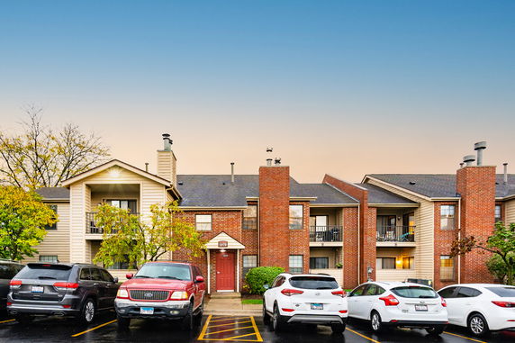 Front view of a multi-story apartment building with multiple balconies and brick exterior.