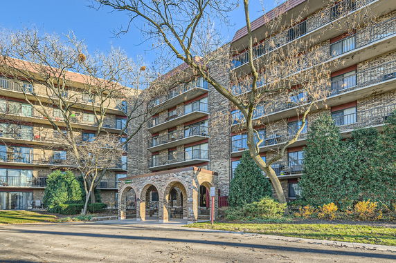 Front view of a multi-story building with balconies and a brick entrance.