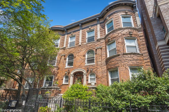 Front view of a multi-story brick building with arched windows and a gated entrance.