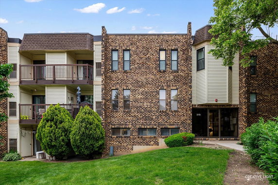 Front view of a multi-story brick apartment building with balconies.