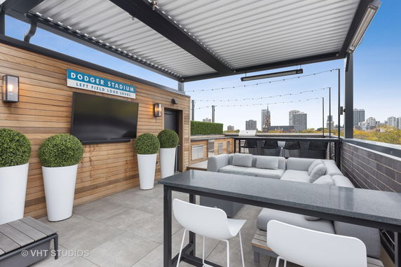 Rooftop lounge area with seating and a television under a pergola.