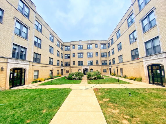 Front view of a multi-story apartment building with a courtyard.