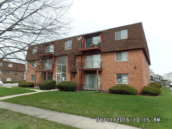 Front view of a multi-story brick apartment building with balconies.