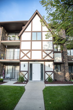 Front view of a multi-story building with a gabled roof and a mix of brick and timber framing.