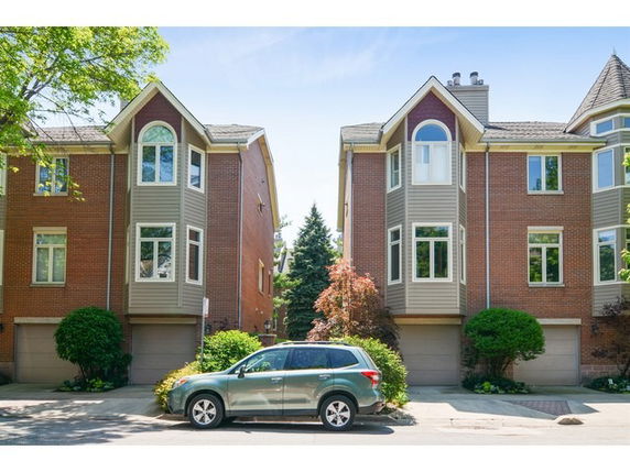 Front view of two adjacent multi-story houses with garages on the ground floor.