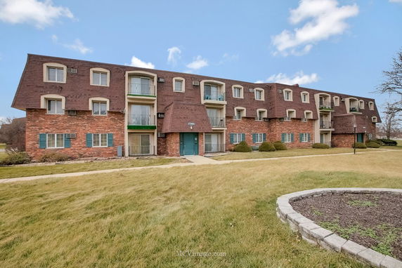 Front view of a three-story brick residential building with balconies.