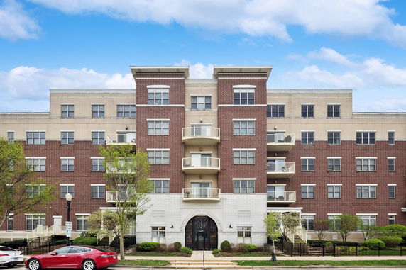 Front view of a multi-story apartment building with red and beige brick facade.
