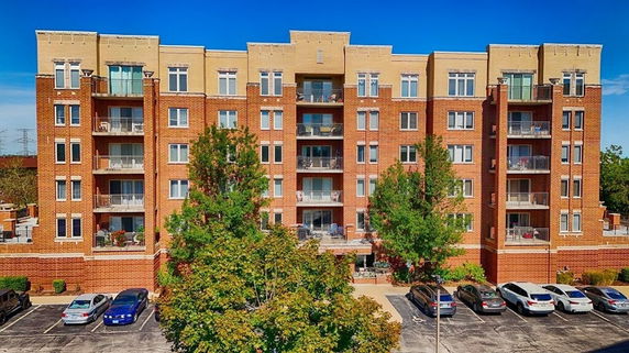 Front view of a multi-story brick apartment building with numerous balconies.