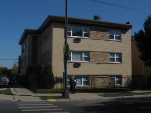Front view of a three-story apartment building with a flat roof and brick facade.