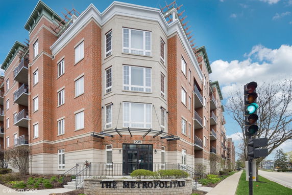 Front view of a multi-story brick residential building named 'The Metropolitan' with balconies and a street view.