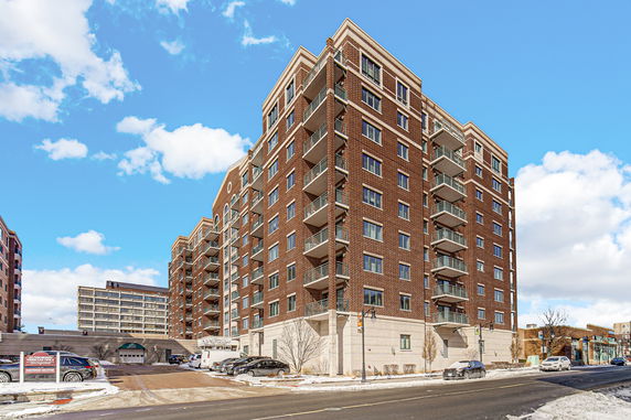Front view of a multi-story brick apartment building with balconies.