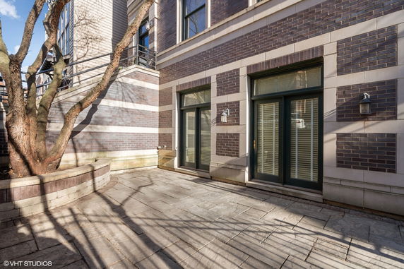 Front view of a building with brick and stone exterior, featuring large patio and glass doors.