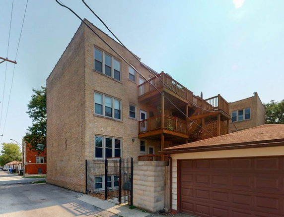 Front view of a multi-story brick building with multiple balconies and a garage.