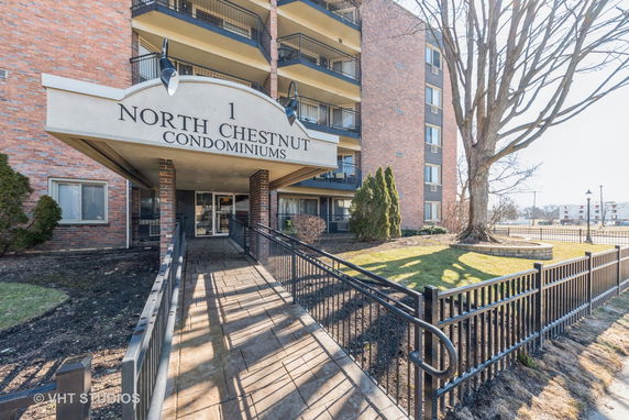 Front view of a condominium building with a brick facade and signage.